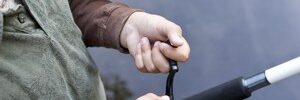 Adult helping a child hold and use a fishing rod near the edge of a body of water.
