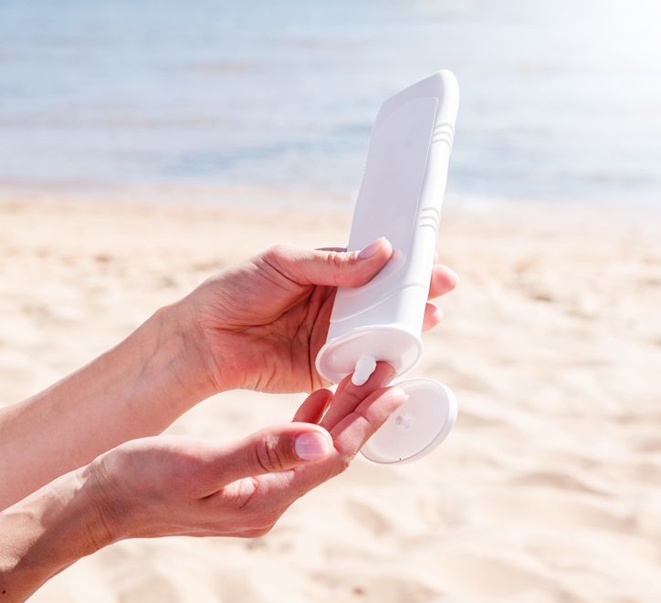 Person putting sunscreen on their hands at the beach